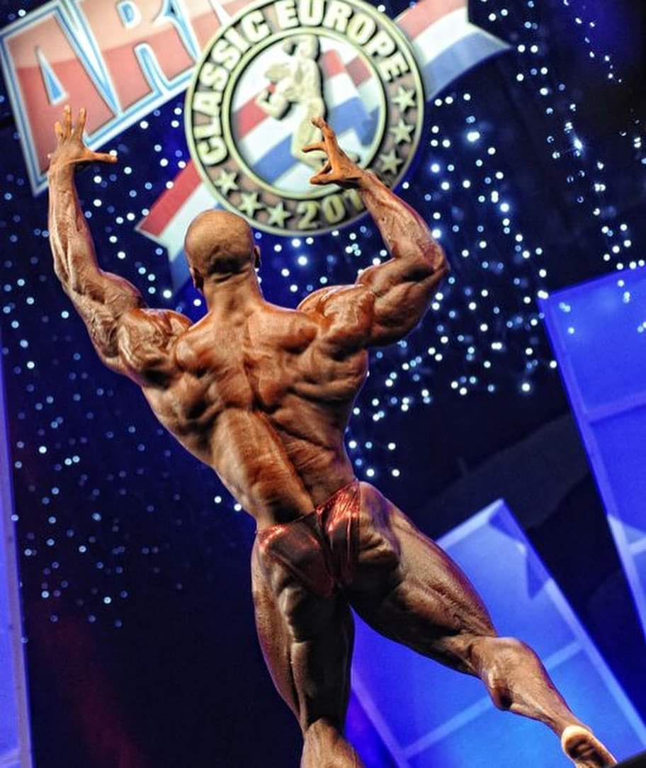 una posa di schiena per Shawn Rhoden sul palco dell'Arnold Classic Europe nel 2011